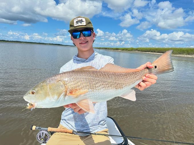 Angler holding a redfish under a blue sky