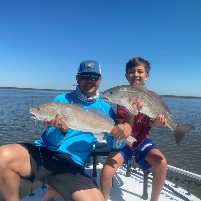 Father and son each holding a redfish