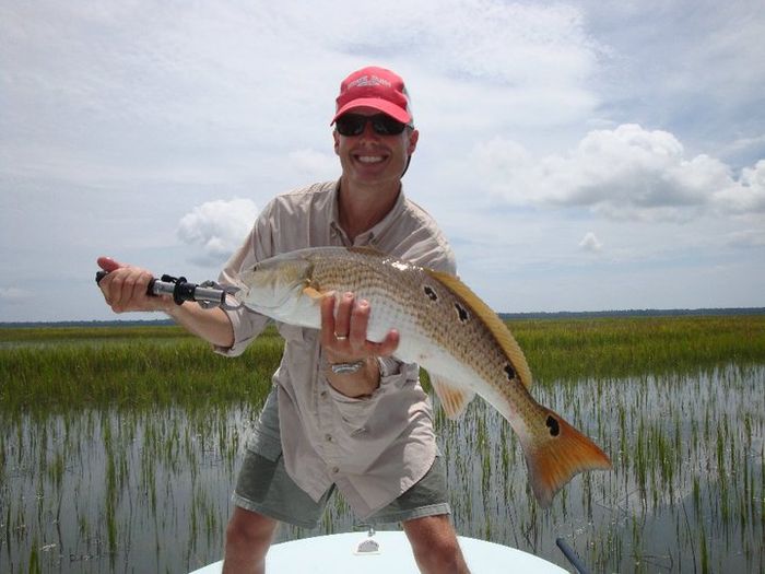 Angler holding a redfish in front of spartina grass