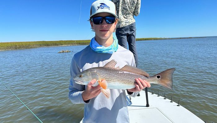 Young angler holding a redfish on the flats