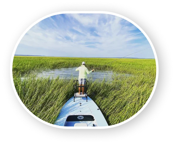 Angler fly fishing from the bow of a skiff in the marsh